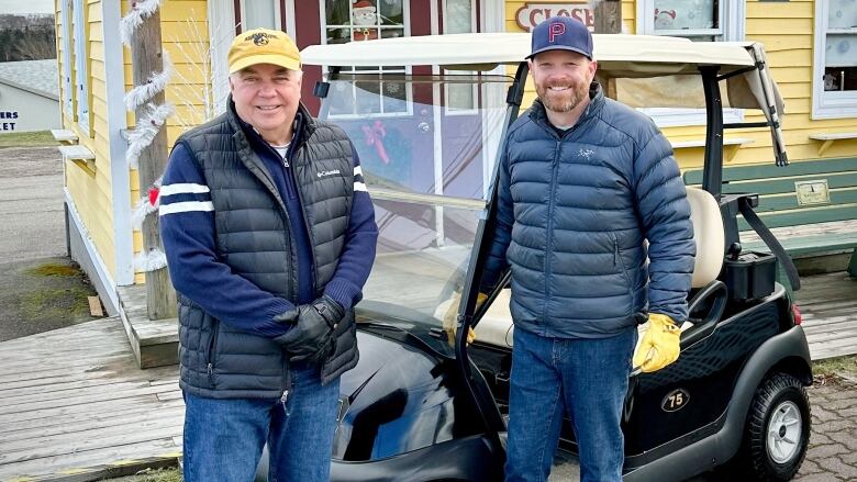 Victoria County Warden Bruce Morrison and Brad MacDonald of Inverary Inn and Resorts show off a golf cart at the visitors welcome centre in Baddeck.