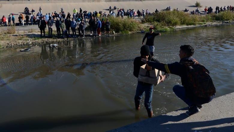 A man and child wait to join a line of migrants at the U.S.-Mexico border.