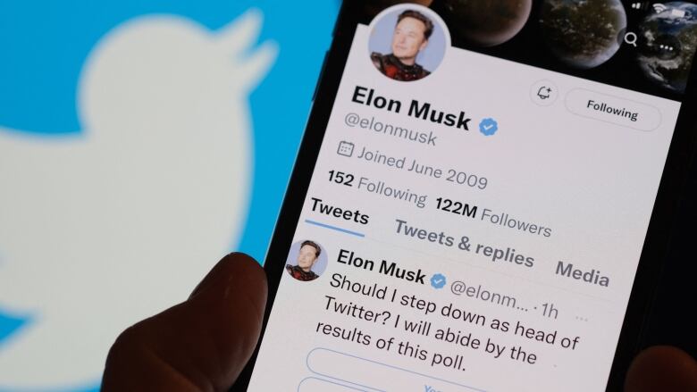 A mobile phone displaying the Twitter social media account of Elon Musk is shown.