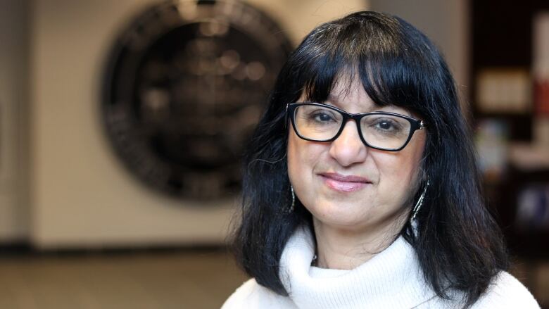 A woman smiles while looking at the camera with a blurry background.