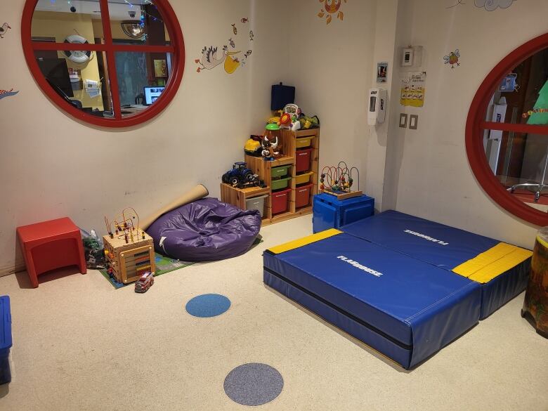 A children's playroom featuring toys, a beanbag chair and mats. 