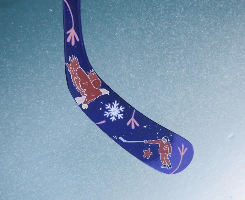 A purple hockey stick with an Indigenous man playing ice hockey, with a depiction of an eagle, star and snowflake. 