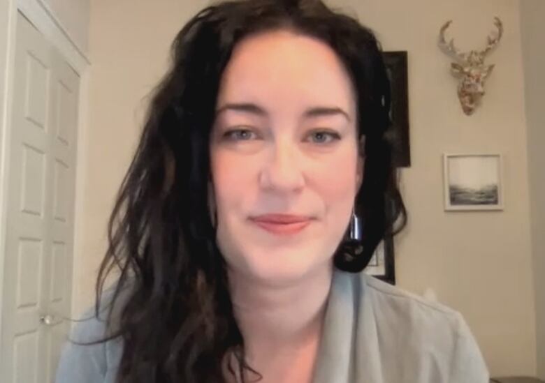 A woman with long dark hair smiles slightly as she looks at the camera.