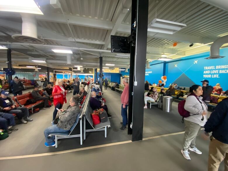 People are sitting at an airport terminal.