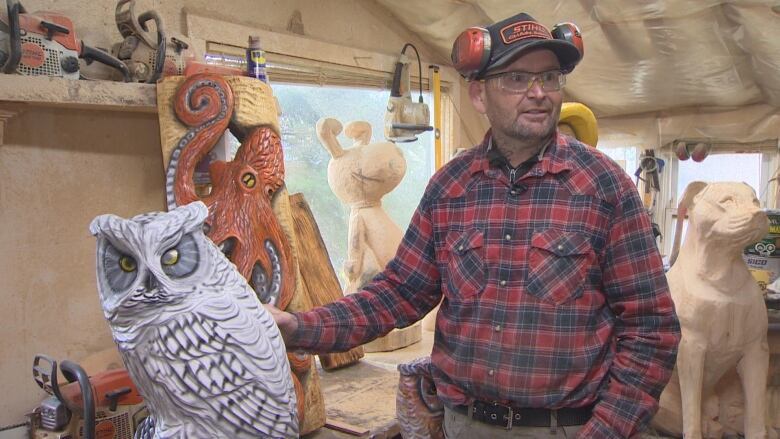 A man stands beside a sculpture of an owl. 