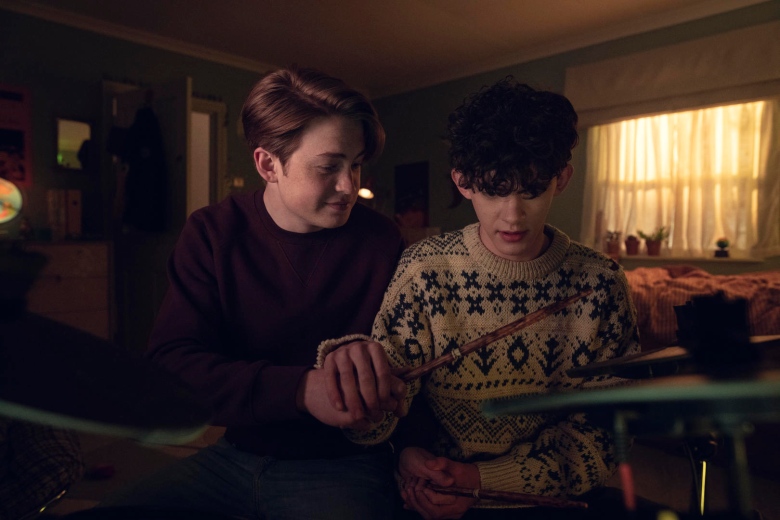 Two young boys playing with a drum set. 