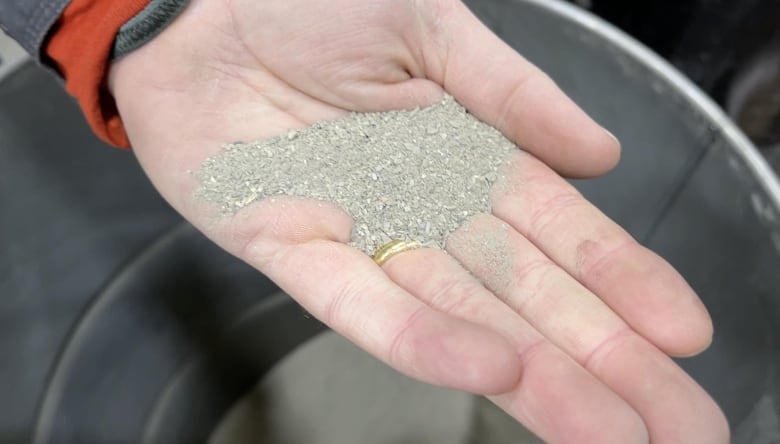 Eric Grand-Maison holds a sample of fine materials following the processing of a catalytic converter. The material will be tested to determine the amount of precious metals. 