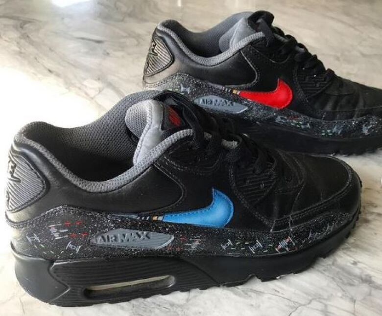 Black sneakers are accented with bright blue and red Nike swooshes made to mimic light sabres. Tiny spaceships battle it out in the trim along the soles.