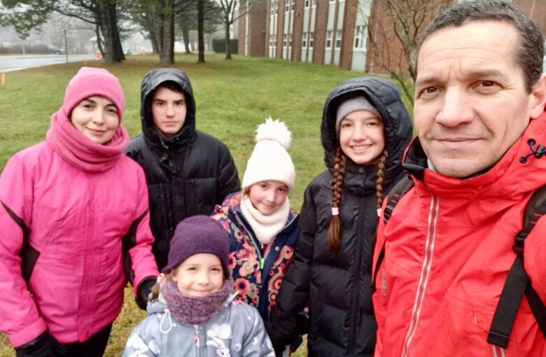 A family wearing winter coats poses for a selfie.