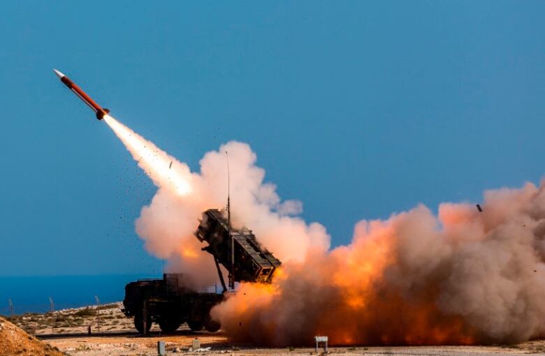 A trail of smoke is seen as a missile flies in the sky on an upward trajectory.