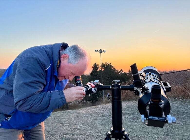 A man stares into a telescope that is pointed toward the sky. 