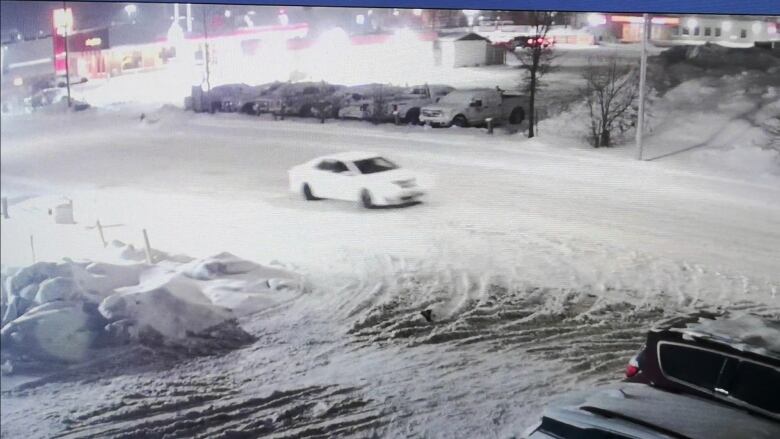 A photo from surveillance footage shows a white car driving down a snow-covered street near where a 37-year-old pedestrian was hit. The vehicle subsequently fled the scene.