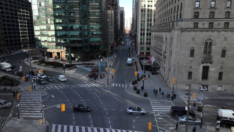 An overhead shot at busy downtown Toronto intersection, where cars and people can be seen. 