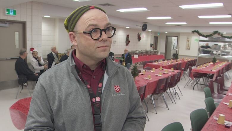 A man stands with his hands crossed in a room inside the city's largest shelter.