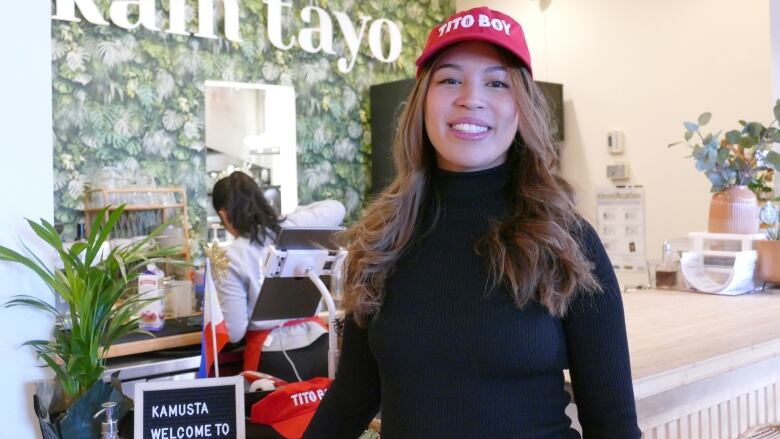 A smiling woman in a red cap reading 