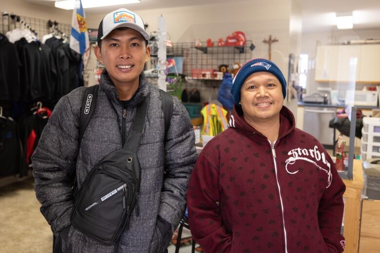 Two men are seen standing together, smiling.