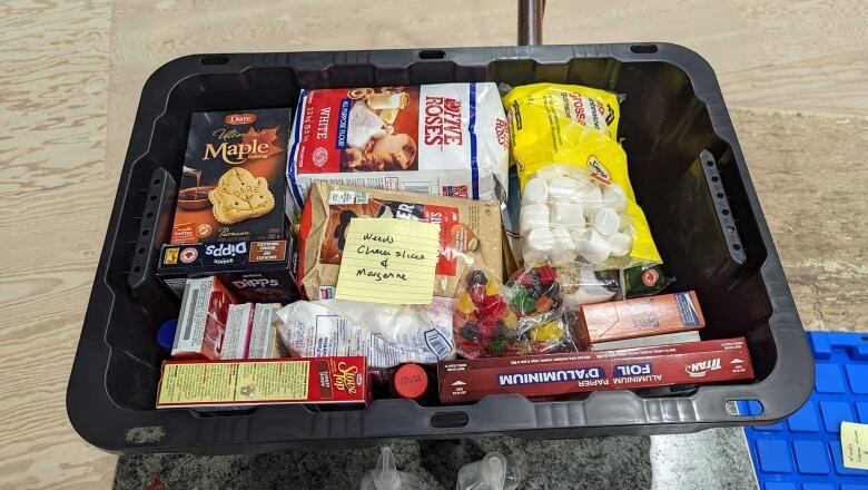 Black bin with flour, cookies, marshmallows and other food. 