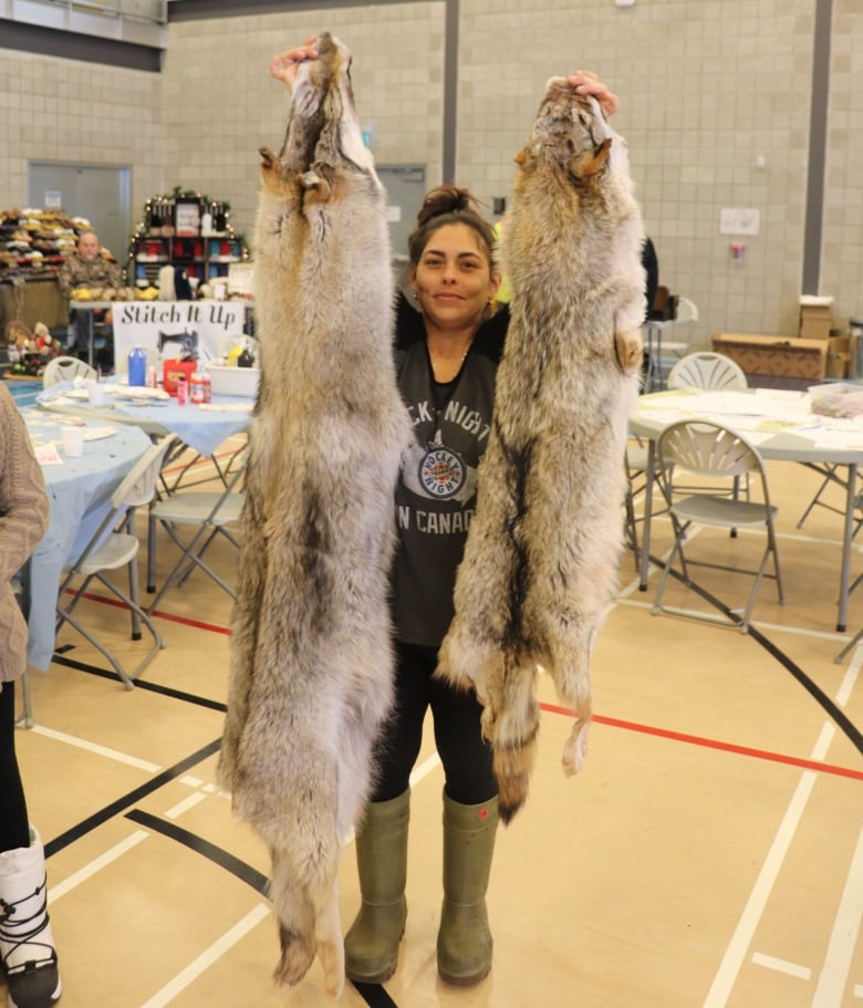 A wolf pelt on the left and coyote pelt on the right are held up to show the varying size