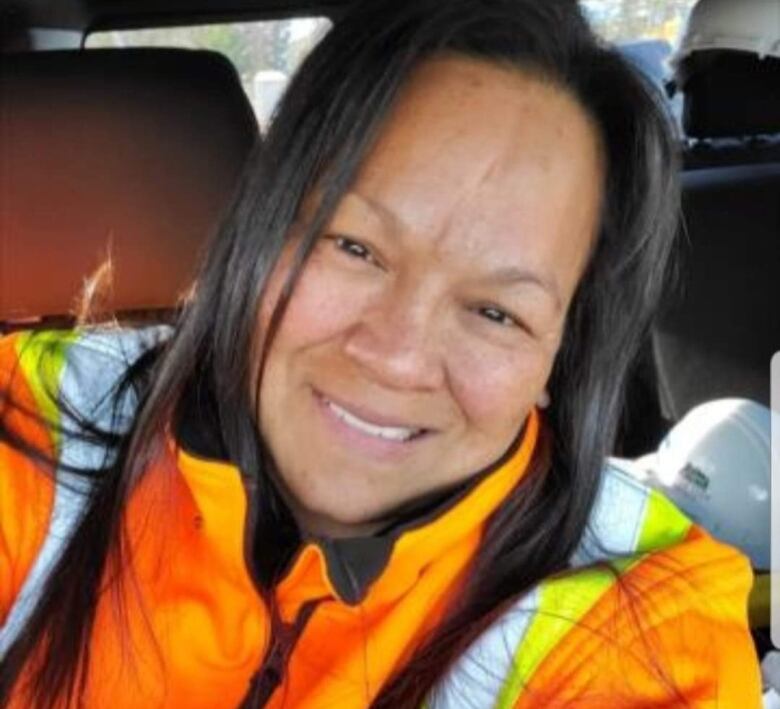 A woman is pictured in a truck with high-visibility clothing.