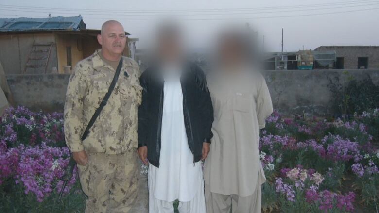 Afghan military interpreters pose with a member of the Canadian Armed Forces. One of the interpreters in the photo says he has been waiting for months to find out if his immigration file to Canada has been approved, and is concerned about his expired Pakistani visa. 