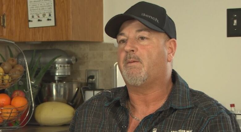 A man stands in the kitchen of a home.