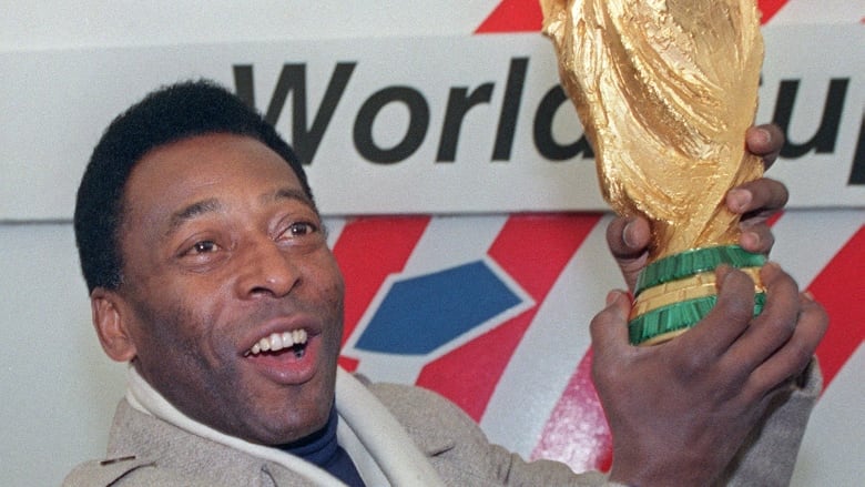 Pele, wearing a suit, is seen holding the shinny and golden World Cup trophy in 1991.