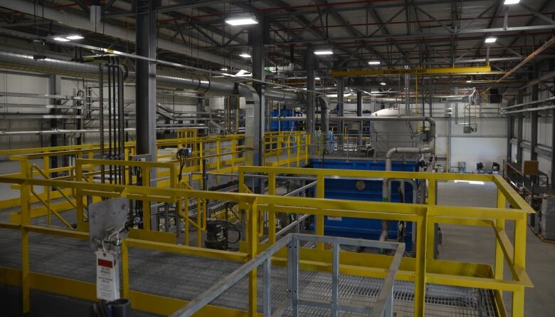 The inside of a water treatment plant with tanks and pipes and colourful railings 