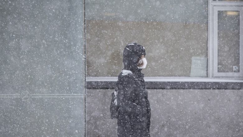 A commuter waits for a street car on Queen St. E. during a significant snowfall on Jan. 17, 2022.