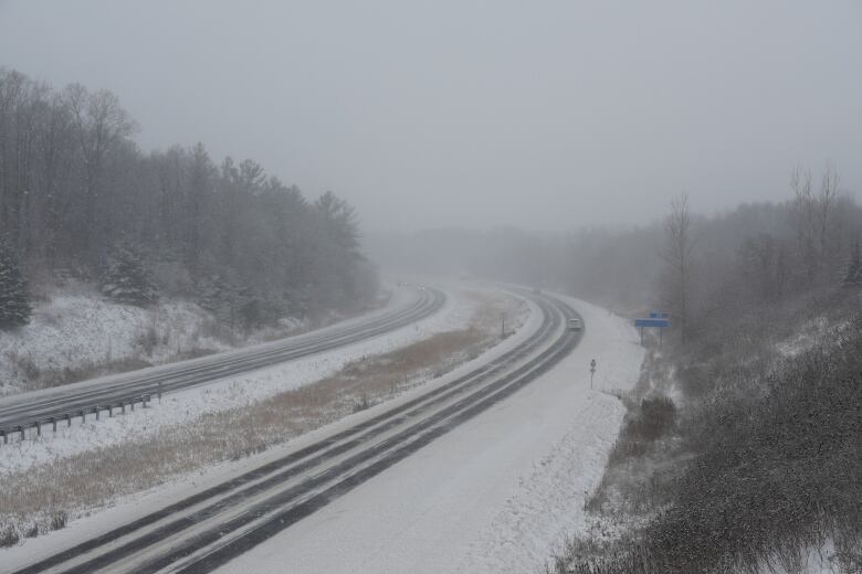 A car drives up a snowy highway. 