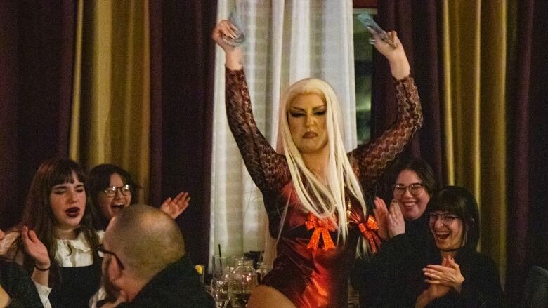 A drag performer dances through an audience.