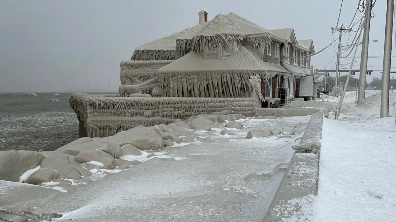 A house covered in ice along the shore of a lake. 