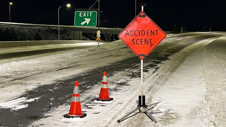 A snowy highway exit, with orange traffic cones and a sign that reads 'ACCIDENT SCENE'. A green 'EXIT' sign is visible in the background.