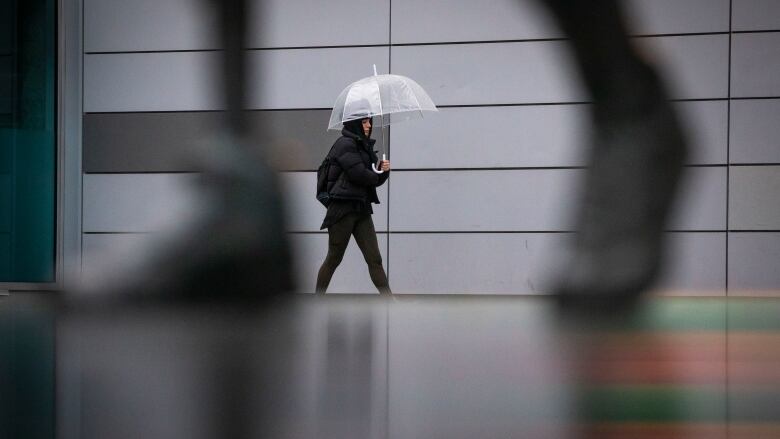 A person is photographed walking in the rain in downtown Vancouver. 