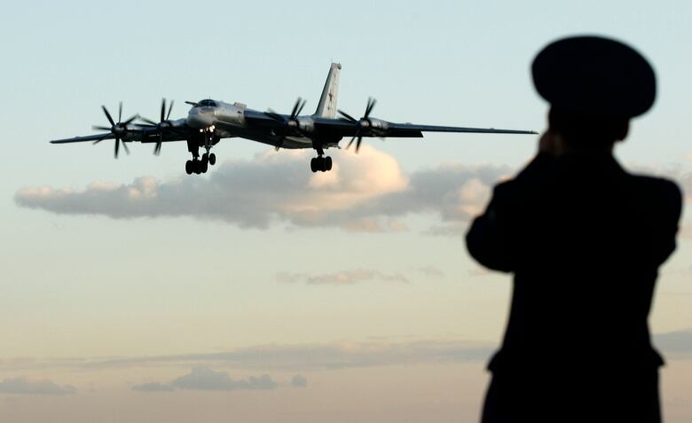 A Russian officer takes a picture of a TU-95 bomber.