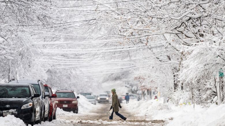 Person walks across snowy street. 