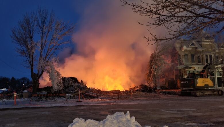 An excavator is parked on the street after a building fire.