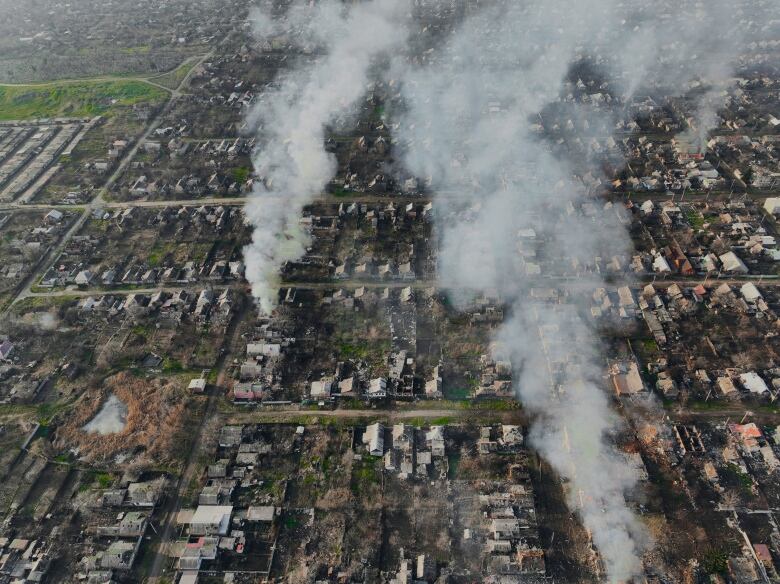 Smoke billows in a war-torn town hit by attacks.