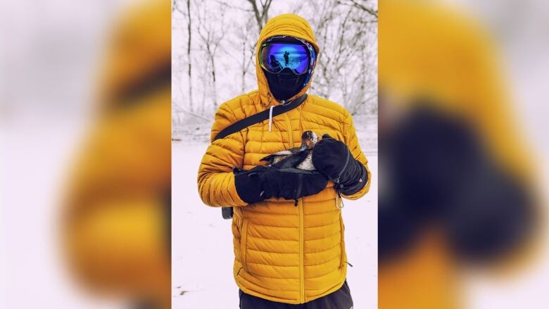 Man holds a duck he just broke out of the ice in his hands