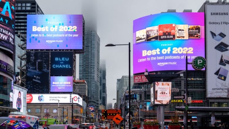 Two large billboard in Yonge and Dundas Square are seen lit up reading 