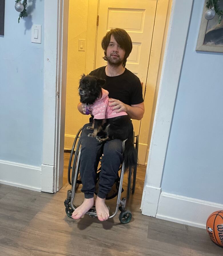 A man sits in a wheelchair with a dog in his lap.