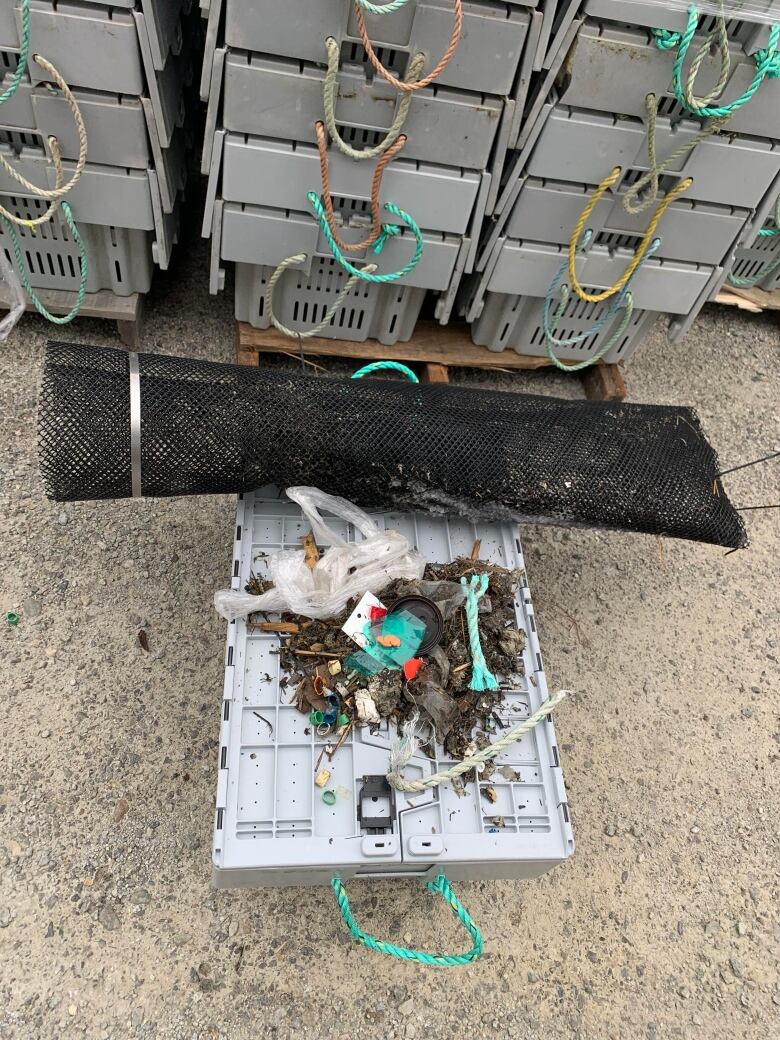 A plastic mesh net is seen beside plastic debris it collected. 