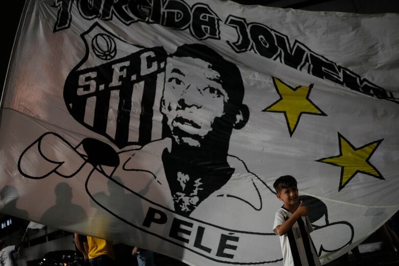 A boy poses next to an image of soccer legend Pele.