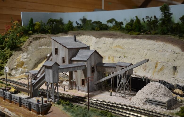 3D replica of a multi-lever galvanized iron gypsum processing building including chutes and a railway track in the foreground.