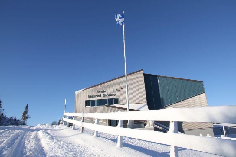 A snow-covered road leads to a school. The sign reads Gabriel Dionne.