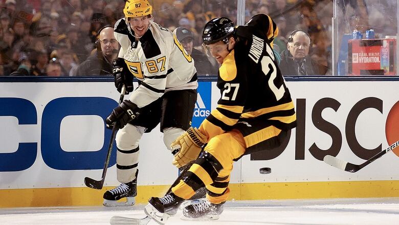 A Penguins and Bruins player battle for puck possession during the NHL Winter Classic at Fenway Park in Boston.