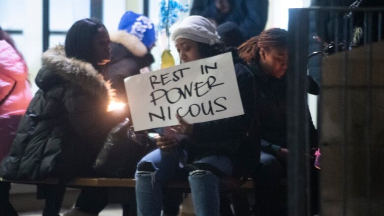 A woman holds a sign that says 