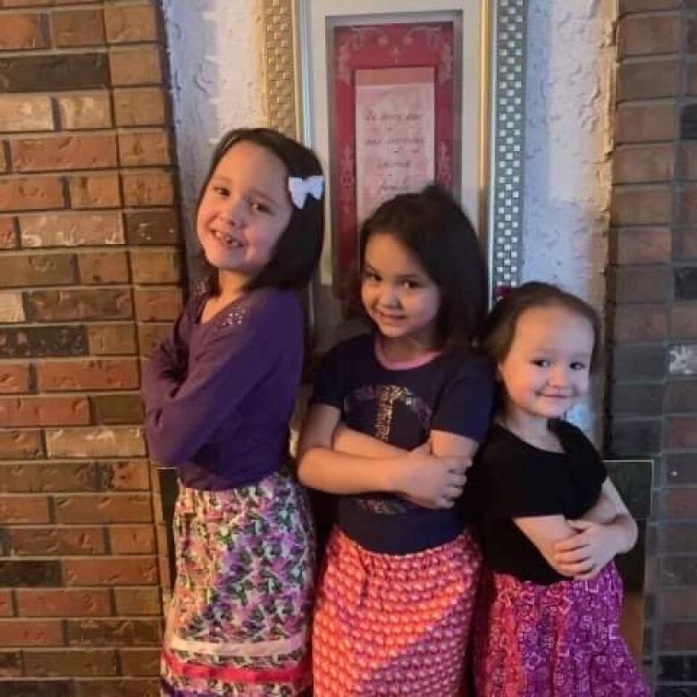 All three girls pose in ribbon skirts gifted to them by their kokum Deena.