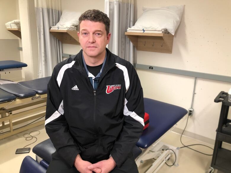 A man sits in an athletic therapist office.