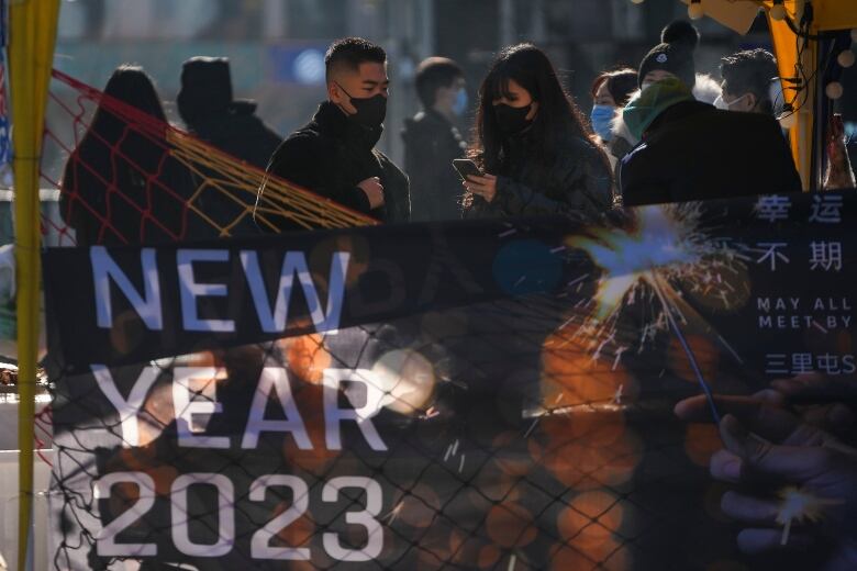 People wearing face masks check their phones on the street in Beijing, China.