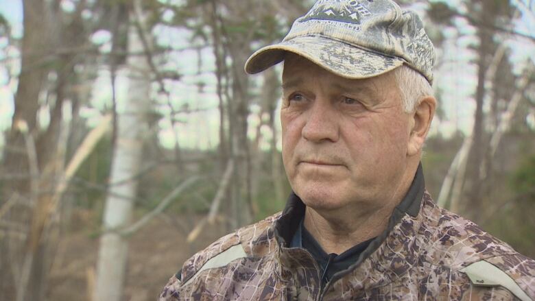 A man stands in a forested area.